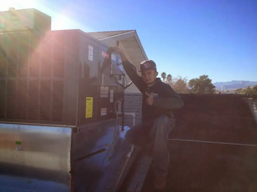 HVAC technician performing Air Duct Cleaning on a rooftop unit in Bruce